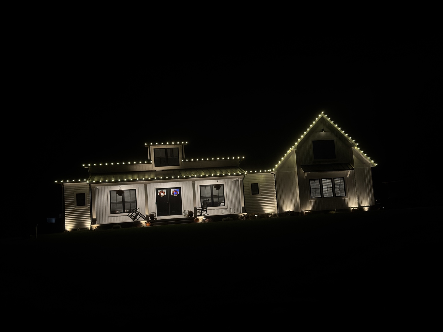 Wide view of warm white permanent lighting on a modern farmhouse