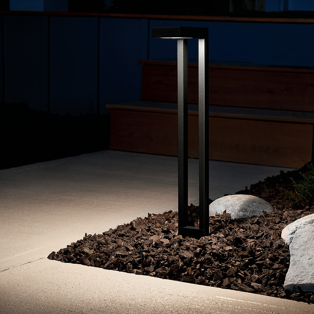Kichler landscape lighting illuminating a home's walkway and planted garden at night